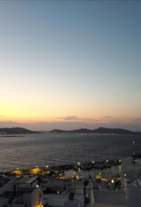 a view of a city with the ocean at sunset at Katerina Apartments & Studios in Naousa