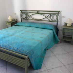 1 dormitorio con 1 cama con edredón azul y 2 mesas en Residence Capo Nord, en Aprilia Marittima