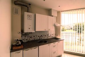a kitchen with white cabinets and a sink and a window at Vienas po kitu in Šventoji