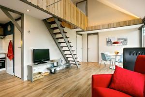 een woonkamer met een rode bank en een trap bij Wad Else in Lauwersoog