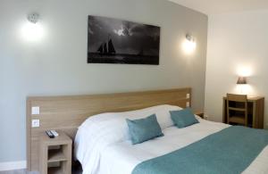 a bedroom with a bed and a sailboat on the wall at Hotel La Voile in Bormes-les-Mimosas