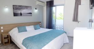 a bedroom with a large bed with blue pillows at Hotel La Voile in Bormes-les-Mimosas