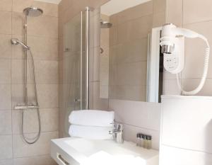 a bathroom with a shower and a sink and a mirror at Hotel La Voile in Bormes-les-Mimosas