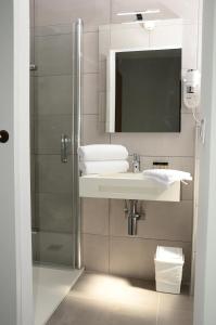 a bathroom with a shower and a sink and a mirror at Hotel La Voile in Bormes-les-Mimosas