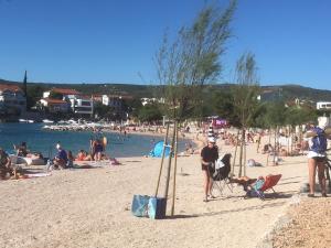 un groupe de personnes sur une plage avec des personnes assises dans l'établissement Villa Vinko, à Rogoznica