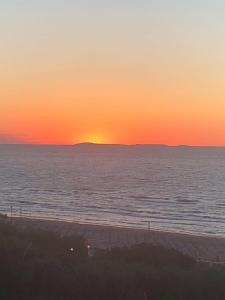 um pôr-do-sol sobre uma praia com o pôr-do-sol à distância em Casa Vacanze "Tramonto sul mare" em Rodi Garganico