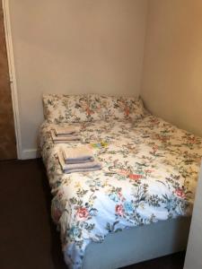 a bed with a floral comforter and towels on it at Pier View b&b for families in Blackpool