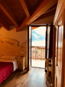 a bedroom with a bed and a sliding glass door at B&B Le Coccole in Molveno