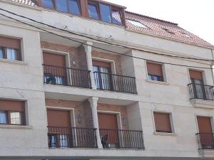 a building with balconies and a cat sitting on a balcony at Apartamentos As Caldelas in O Grove