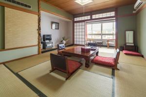 a living room with a table and chairs and a television at Shoei Daini Bekkan in Kochi