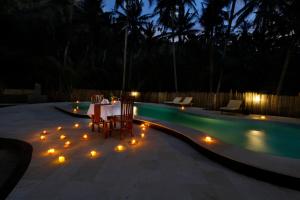 a patio with a table and lights next to a swimming pool at Crystal Bay Villa in Nusa Penida