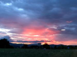 una puesta de sol en un campo con un cielo nublado en Logis Hôtel Volcan Sancy, en Nébouzat