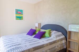 イエールにあるSoleil d´Azurのベッドルーム1室(紫と緑の枕が備わるベッド1台付)