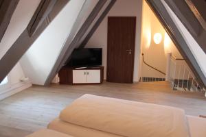 a attic room with a bed and a television at Hotel Schmales Haus in Ulm