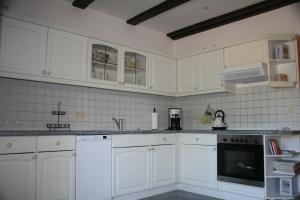 a kitchen with white cabinets and white appliances at Ferienhaus Straupitz-Spreewald mit Sauna in Straupitz