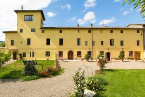 a large yellow building with a yard with flowers at Fattoria il Casone in Monteriggioni