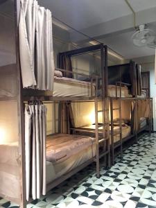 two bunk beds in a room with a checkered floor at Chato Hostel in Pakse