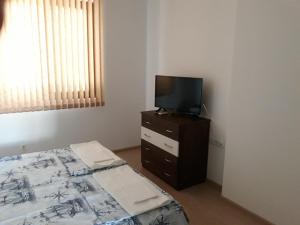 1 dormitorio con cama y vestidor con TV en Апартамент Явор en Balchik