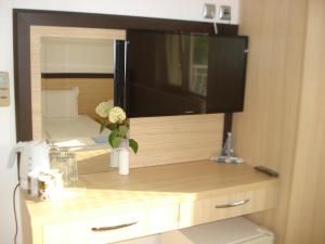 a flat screen tv on top of a wooden cabinet at The Sunny Home Guesthouse in Chernomorets