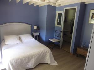 1 dormitorio con cama blanca y pared azul en Kerverh, en Landévant