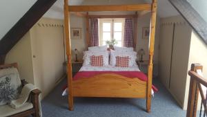 una camera con letto a baldacchino in legno e cuscini di La Metairie & Cottages a Camors Altre 46 foto