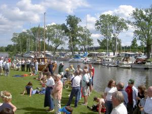 una multitud de personas de pie en el césped cerca de un puerto deportivo en Wassbacken Vandrarhem, en Töreboda