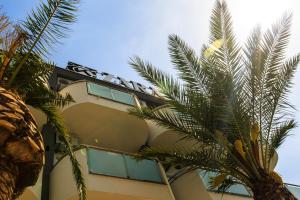 a building with palm trees in front of it at Zara apartmani Sutomore in Sutomore