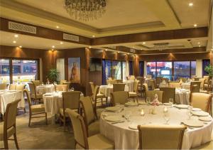 a restaurant with white tables and chairs and a chandelier at Thousand Nights Hotel in Amman