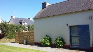 Clohars-CarnoëtにあるLes vacances aux Poulduの青い扉と二本の植物のある白い建物