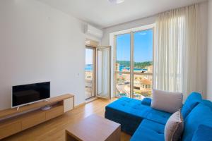 a living room with a blue couch and a large window at Eukaliptus in Bečići