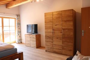 1 dormitorio con un gran armario de madera y TV en Ferienwohnung Pferdehof Pankratz en Iffeldorf