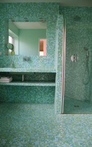 a green tiled bathroom with a shower and a mirror at Fare Bambou in Gujan-Mestras