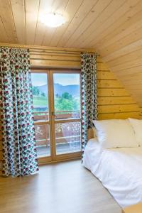 a bedroom with a bed and a large window at Domki u Huberta in Grywałd