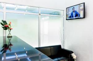 a living room with a glass table and a tv on a wall at Al Jisr Hotel in Muscat