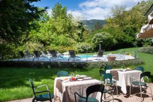 um pátio com mesas e cadeiras e uma piscina em Vital Hotel Flora em Comano Terme