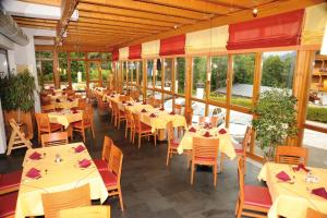 ein Restaurant mit Tischen, Stühlen und Fenstern in der Unterkunft Marco Polo Alpina Familien- & Sporthotel in Maria Alm am Steinernen Meer