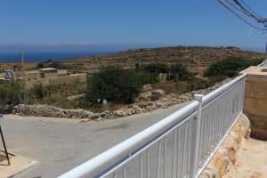 d'un balcon avec une clôture blanche et une vue sur l'océan. dans l'établissement Simar, à Qala