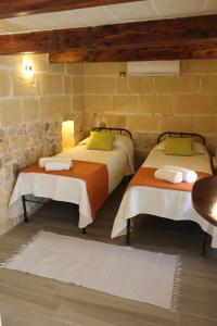 two beds in a room with a stone wall at Simar in Qala