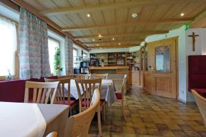 a restaurant with tables and chairs and a cross on the wall at Pension Arnica B&B in San Vigilio Di Marebbe
