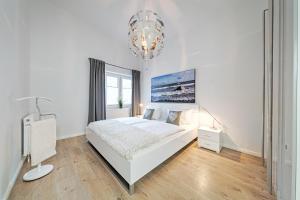 - une chambre blanche avec un lit et un lustre dans l'établissement Ferienwohnung Meeschendorf, à Fehmarn