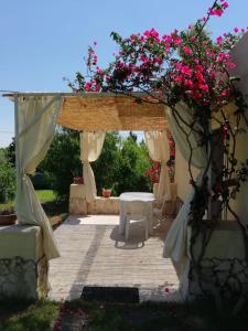 a pavilion with a white table and pink flowers at Borgo degli Ulivi Depandance in Capoterra