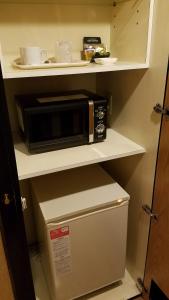 a microwave sitting on top of a refrigerator in a kitchen at Hotel Mermaid (Adult Only) in Miura