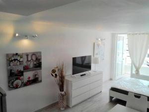 a white bedroom with a television and a white dresser at Borinquen Private Homes in Playa de las Americas