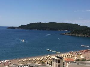 a beach with umbrellas and a boat in the water at Eukaliptus in Bečići