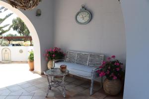 una panchina, un tavolo e un orologio su un muro di Ammos Naxos Exclusive Apartments & Studios a Naxos Chora