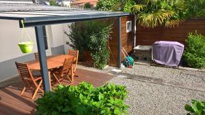 um deque de madeira com uma mesa e cadeiras sob um guarda-sol em Gîte Studio Tarbes Pyrénées em Tarbes