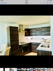 a kitchen with wooden cabinets and a stove top oven at Luxury 2 Bedroom Apartment in Prime City Location in Belfast