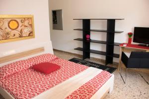 una camera con letto con coperta rossa e scrivania di B&B Myrta Maria a Cagliari