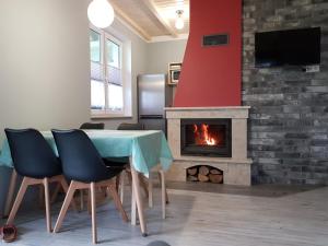 a dining room with a table and a fireplace at Domki Cyranowka in Lubiatowo