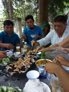 un grupo de personas sentadas alrededor de una mesa comiendo comida en Khách sạn Mộng An en Vĩnh Hy